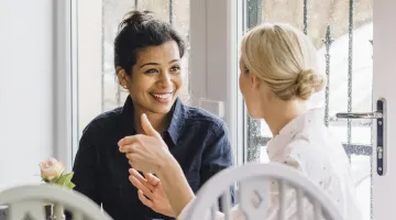 two young women talking in a cafe over coffee